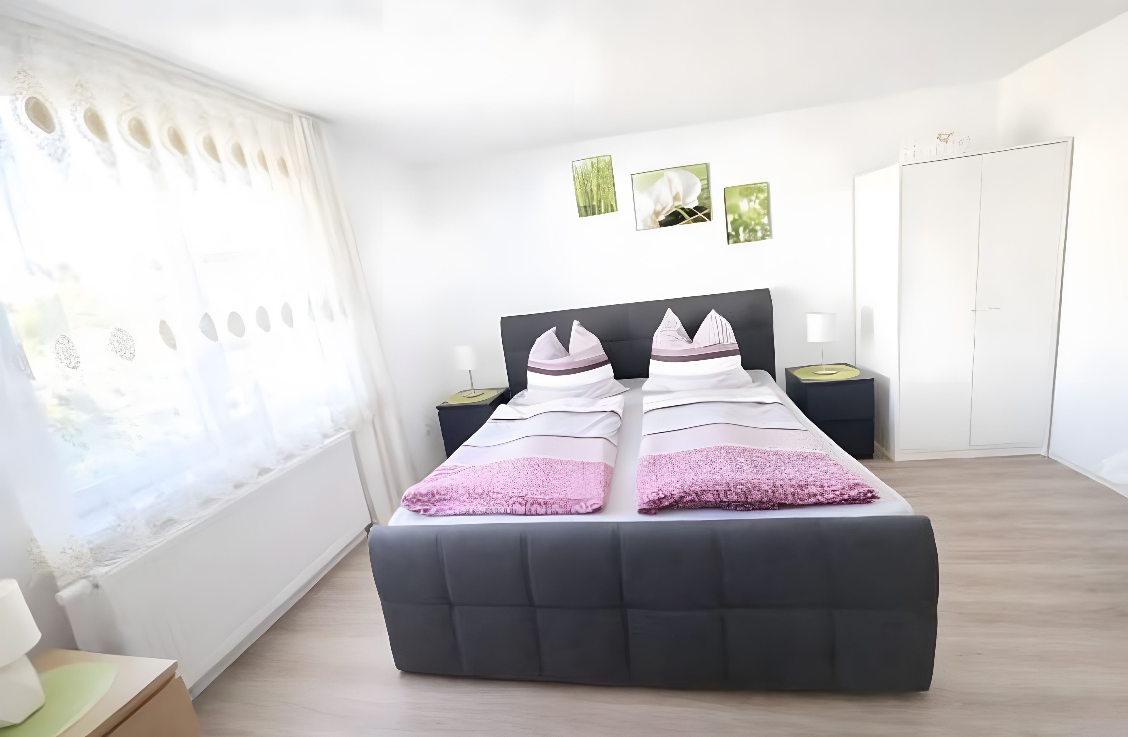 Ein Schlafzimmer mit einem Bett, Nachttischen, einem Kleiderschrank und einem Fenster mit Vorhängen.