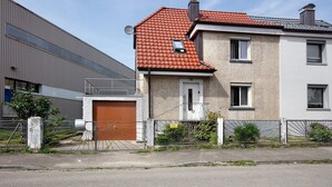 Ein Wohngebäude mit rotem Ziegeldach, geschlossenem Eingangstor und einer Satellitenschüssel.