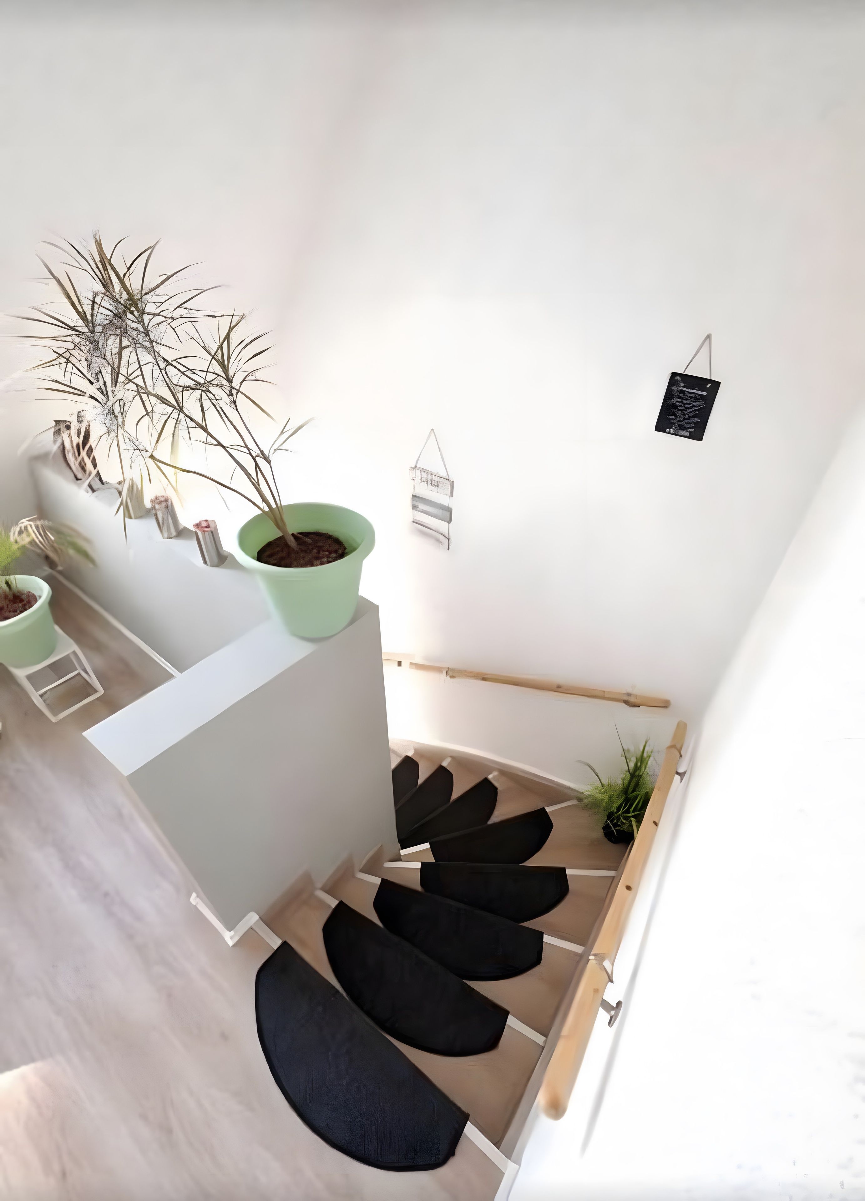 A staircase with black cushioned steps, a green plant pot, and a small hanging decoration.