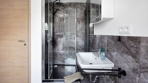 Ein modernes Badezimmer mit Dusche, Waschbecken und Handtuchhalter.