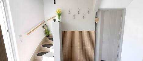 Un interior moderno con una escalera, una planta en la pared y un adorno mural.