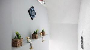 Eine Wand mit Wanddeko, drei quadratische gewebte Pflanzgefäße mit Kakteen und eine kleine Figur.