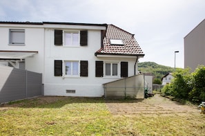 A two-story house with a sloped roof, a covered porch, and a fenced yard. - Holiday Home 'Ayna' with Private Terrace, Private Garden and Wi-Fi (Bad Säckingen)