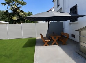 A patio area with a table and chairs, a large umbrella, and a green lawn. - Holiday Home 'Ayna' with Private Terrace, Private Garden and Wi-Fi (Bad Säckingen)