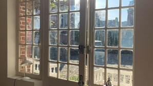 Una habitación con un ventanal grande, una puerta y una pequeña mesa con un farol.