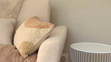 Una sala de estar moderna con un sofá, un plaid y una mesita auxiliar blanca de estructura metálica.