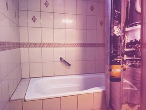 Bathroom features a bathtub, shower curtain, and tiled walls.