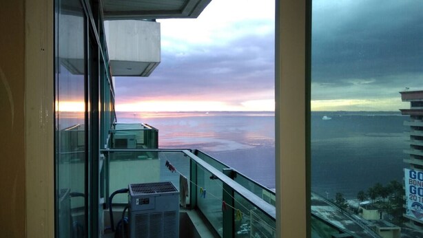 Een balkon met uitzicht op de oceaan en een zonsondergang.