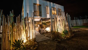 A modern house with a wooden deck, surrounded by cacti and plants.
