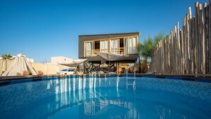 A swimming pool with a wooden deck and a building with large windows in the background.