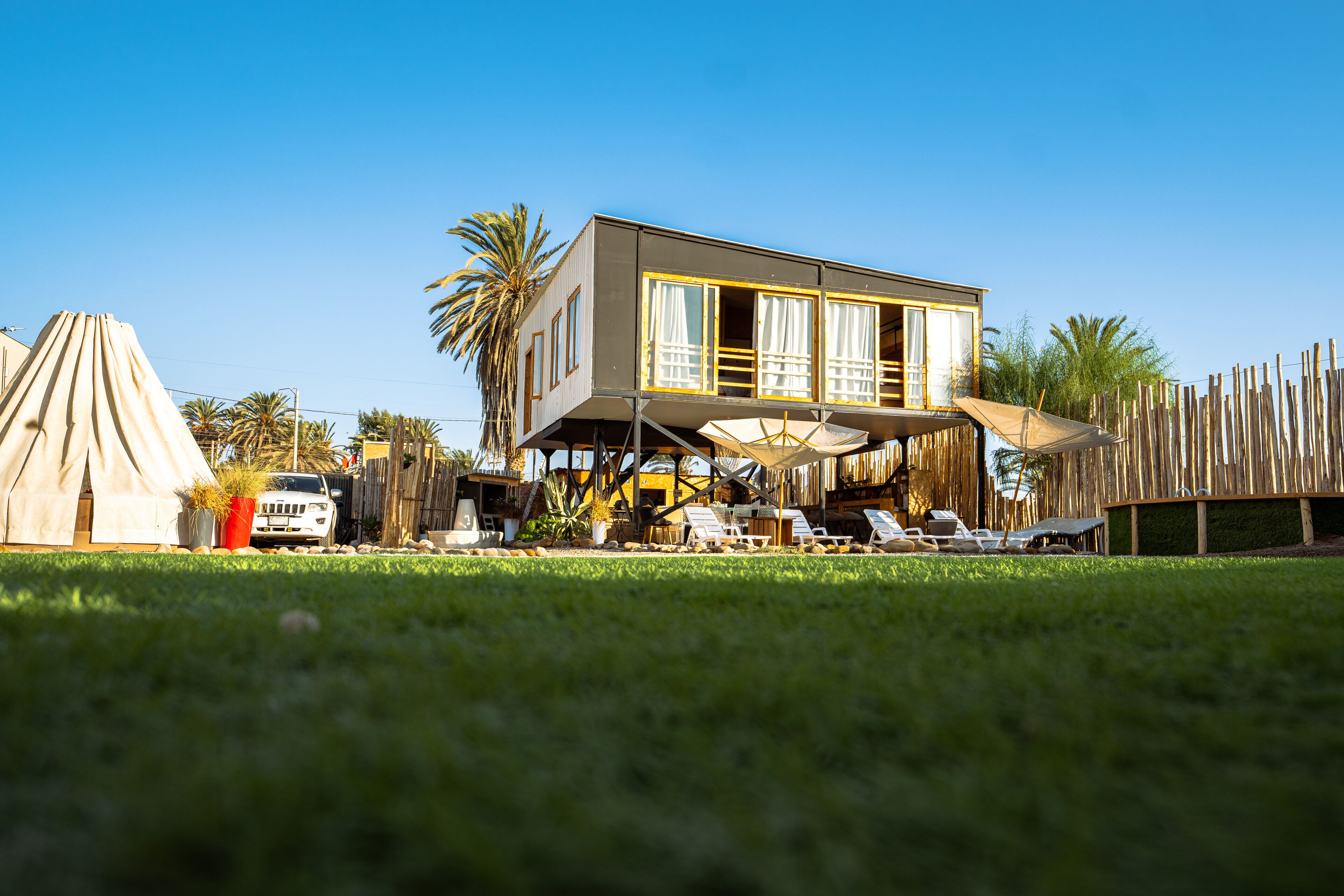 A two-story house with a balcony, a tent, and a white car.