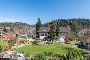 Un quartier résidentiel avec des maisons, une pelouse bien entretenue et une colline boisée en arrière-plan.