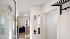 Een hotelgangen met een glazen deur waarop 'EGGE-RESORT' staat, een spiegel aan de muur en een blauwe bank op de achtergrond.