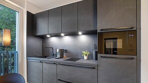 Een moderne keuken met donkere kastjes, een inbouwoven en een koffiezetapparaat.