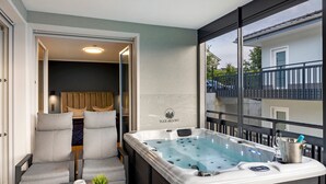 Een hottub met uitzicht op een gebouw, een zithoek met stoelen en een kleine tafel met een plant.