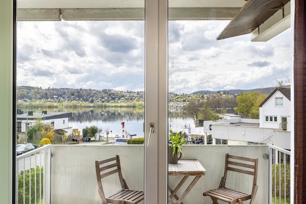Ein Balkon mit zwei Holzstühlen, einem kleinen Tisch und einem Blumentopf.