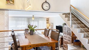A dining area with a wooden table, chairs, a clock, and a staircase. - Edersee-Scheid Apartment with Lake View, Private Terrace & Wi-Fi (Waldeck-Scheid)