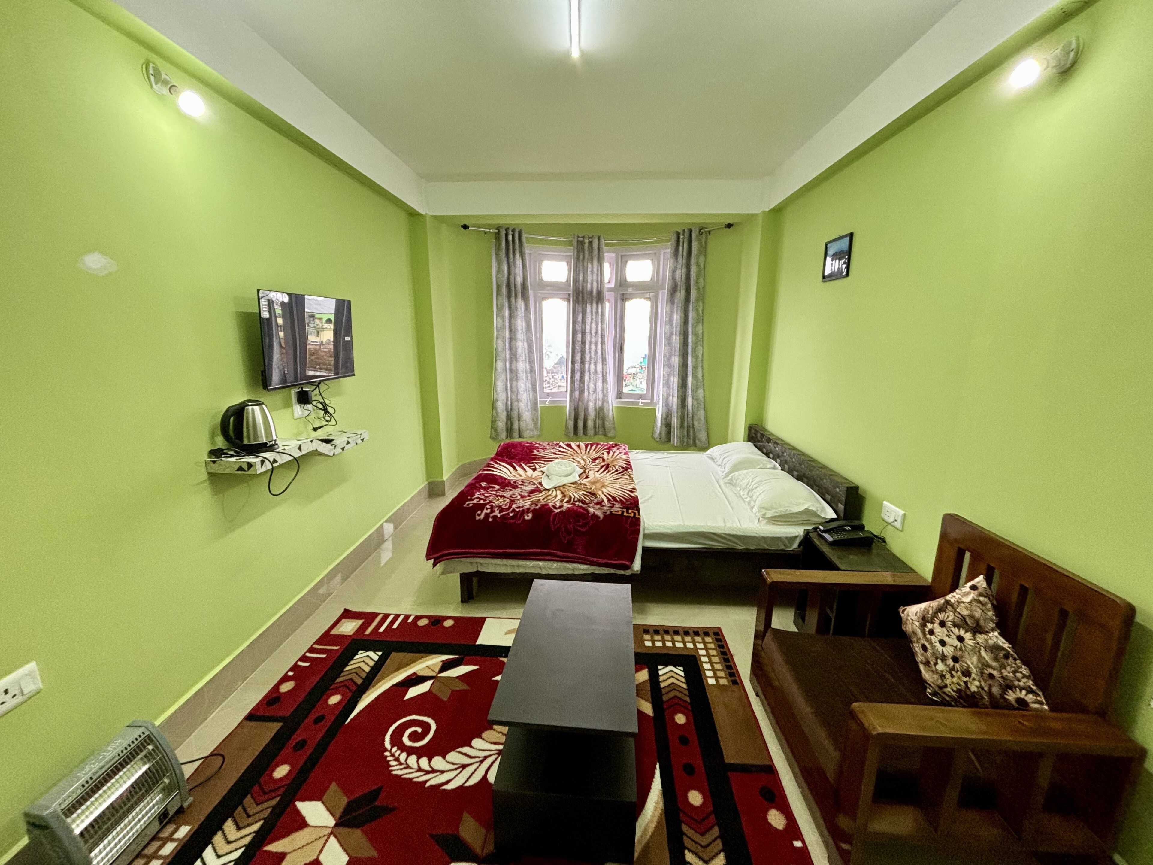 A room with two beds, a TV, a heater, and a window with curtains.