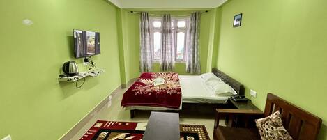 A room with two beds, a TV, a heater, and a window with curtains.