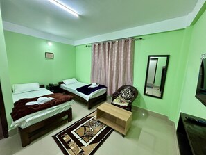 A room with two beds, a chair, a mirror, and a small table. - Hotel Vivid Tawang (Tawang)