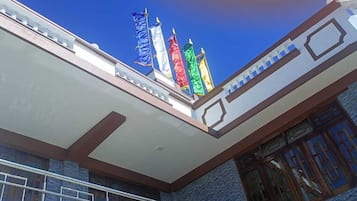 Um edifício com varanda, escadaria e janela com moldura azul.