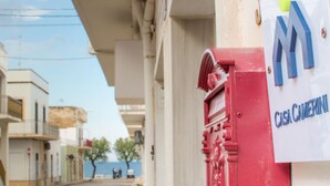 A street view with buildings, a red mailbox, and a sign reading "Casa Caverni". - Casa Camerini in Villanova (Ostuni)