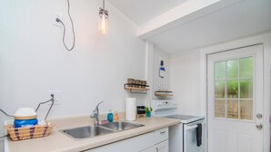 A kitchen with white cabinets, a double sink, a stove, and a refrigerator. - The Cottage in Clearwater - 30 Day Minimum Stay (Clearwater)