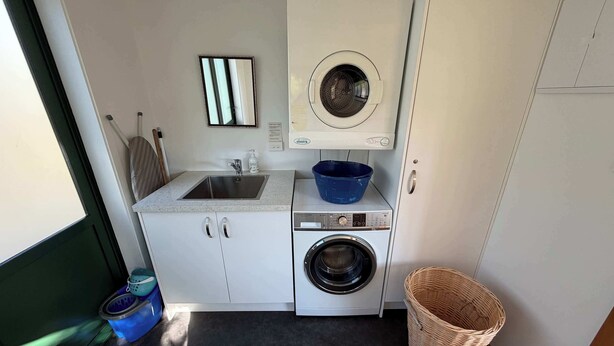 A compact laundry area with a washing machine, a sink, and a blue basin. - Tata Beach Heights - Spectacular Ocean and Bush Views (Tata Beach)