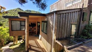 Una cabaña de madera con porche cubierto, una bicicleta y vistas del bosque circundante.