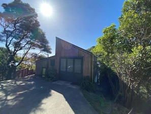 A modern house with a sloped roof, large windows, and a wooden exterior. - Tata Beach Heights - Spectacular Ocean and Bush Views (Tata Beach)