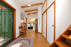 A hallway with wooden beams, a chair, a bookshelf, and a patterned rug. - Tata Beach Heights - Spectacular Ocean and Bush Views (Tata Beach)