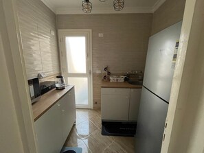 Kitchen equipped with oven, refrigerator, coffee maker, and kettle.