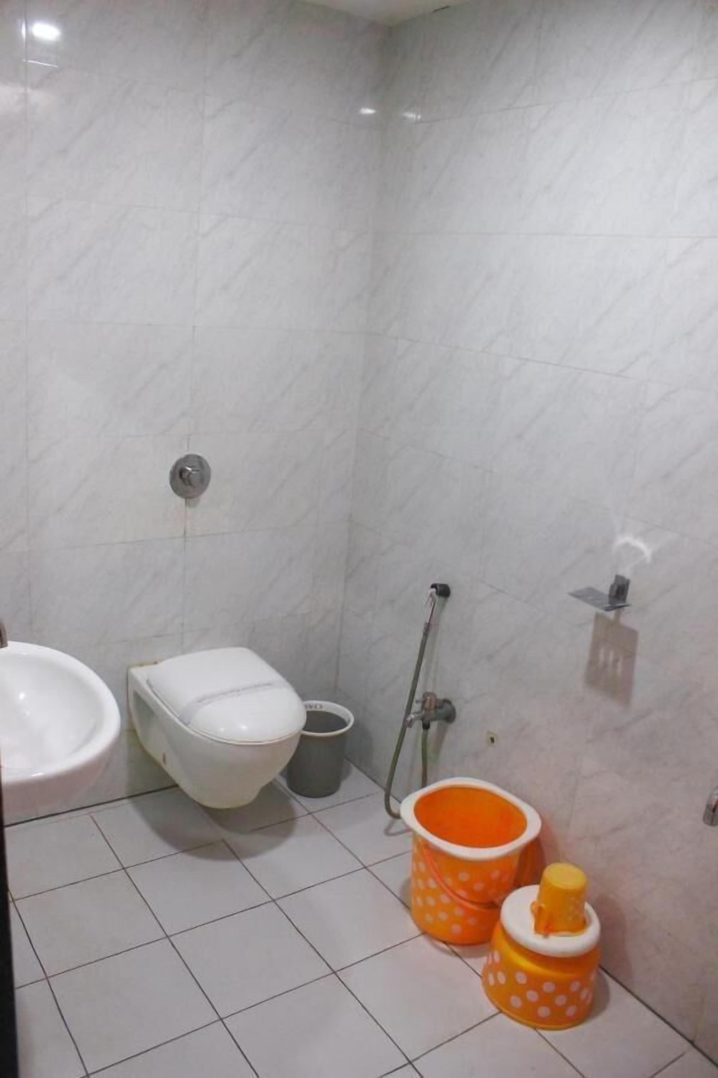 A bathroom with a toilet, bidet, and a mop.