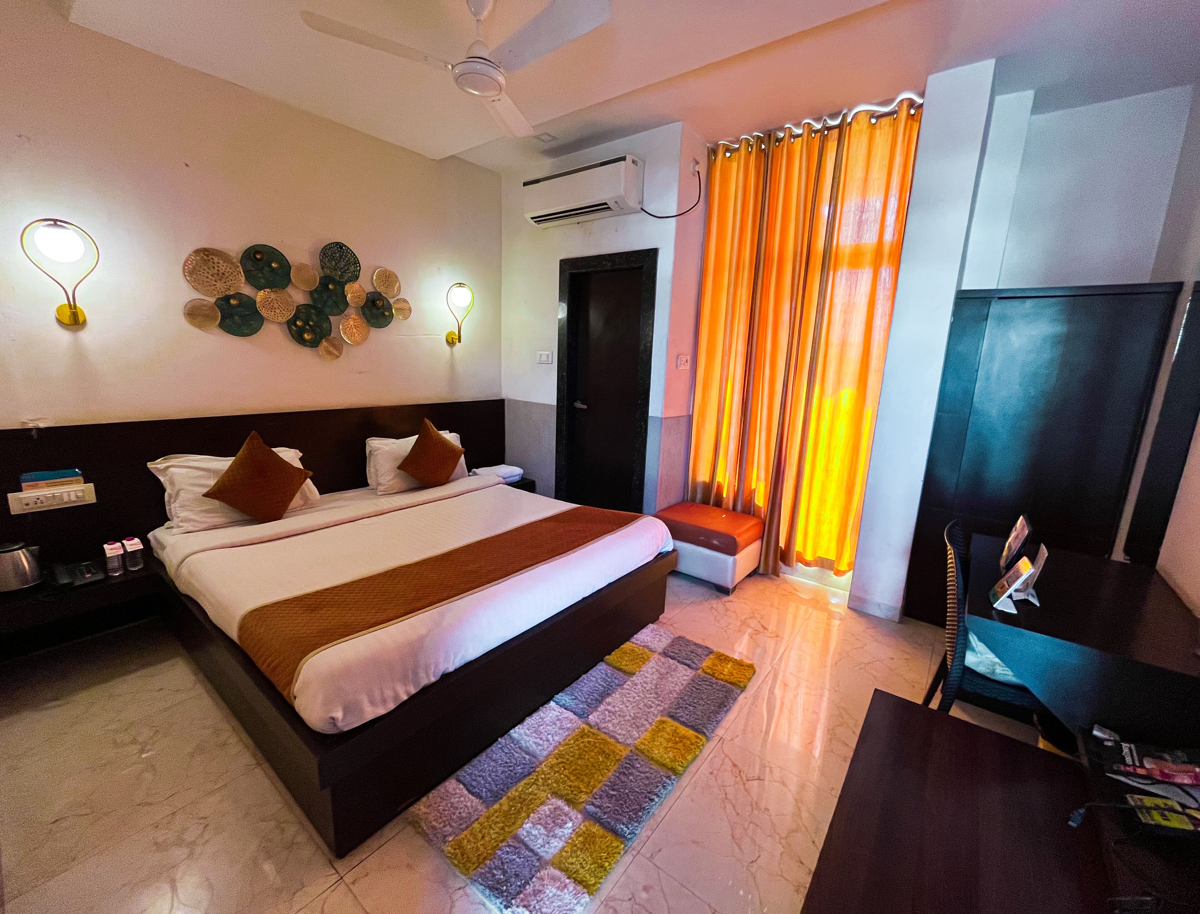 Une chambre d’hôtel avec un grand lit, un bureau, une chaise, une télévision et une fenêtre avec des rideaux.