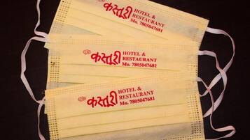 Três máscaras faciais amarelas com texto impresso em um alfabeto não latino, possivelmente indicando um hotel ou restaurante.