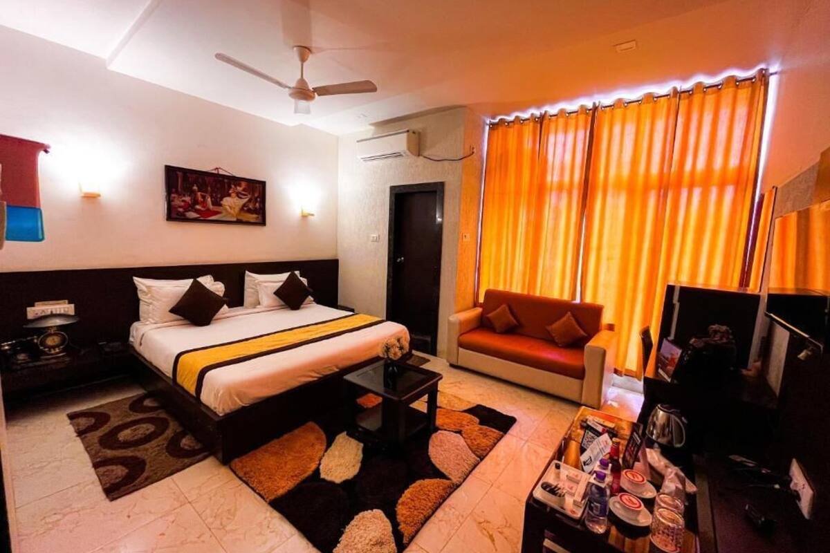 A hotel room with a bed, a sofa, a coffee table, and a TV.