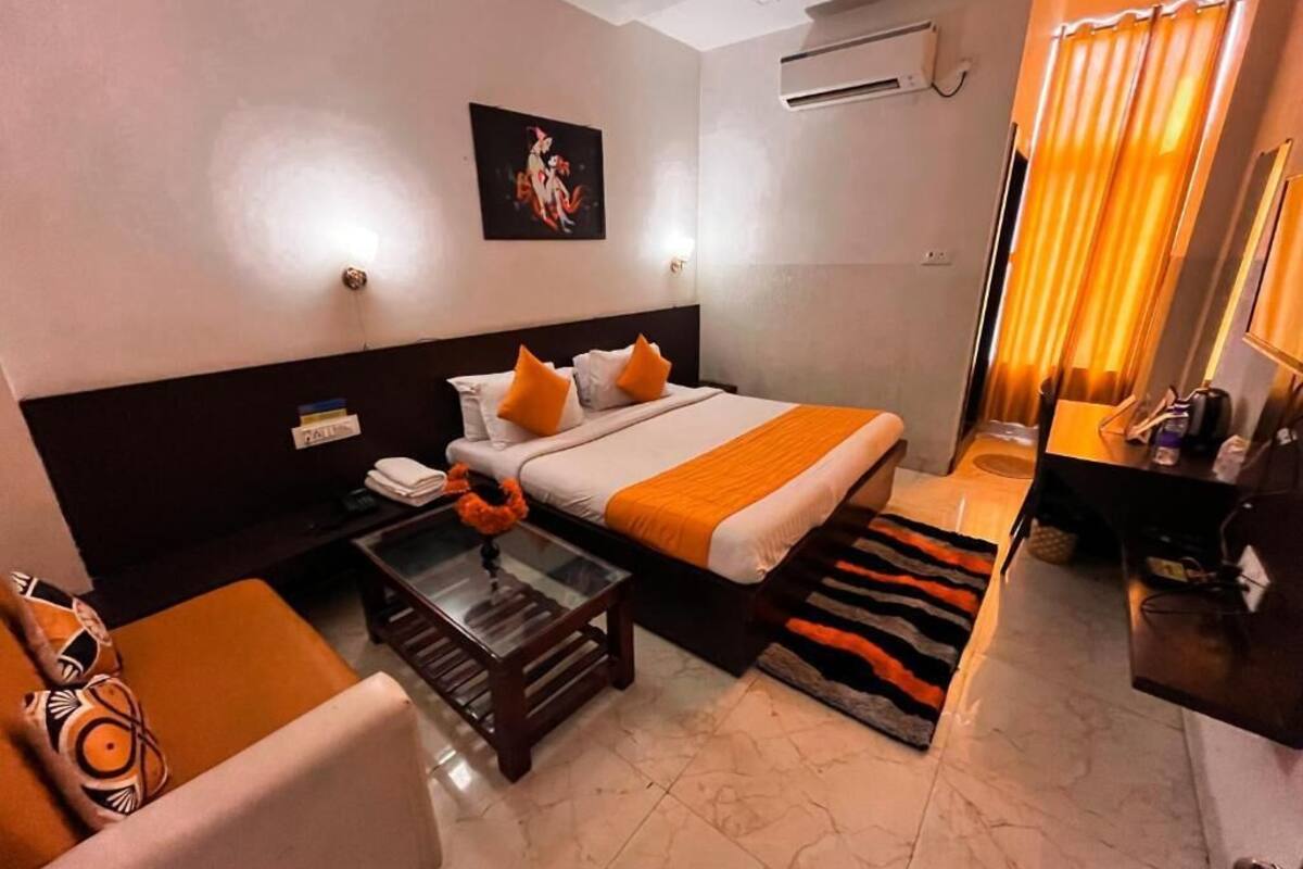 A hotel room with a bed, a desk, a chair, a small table, and a sofa.
