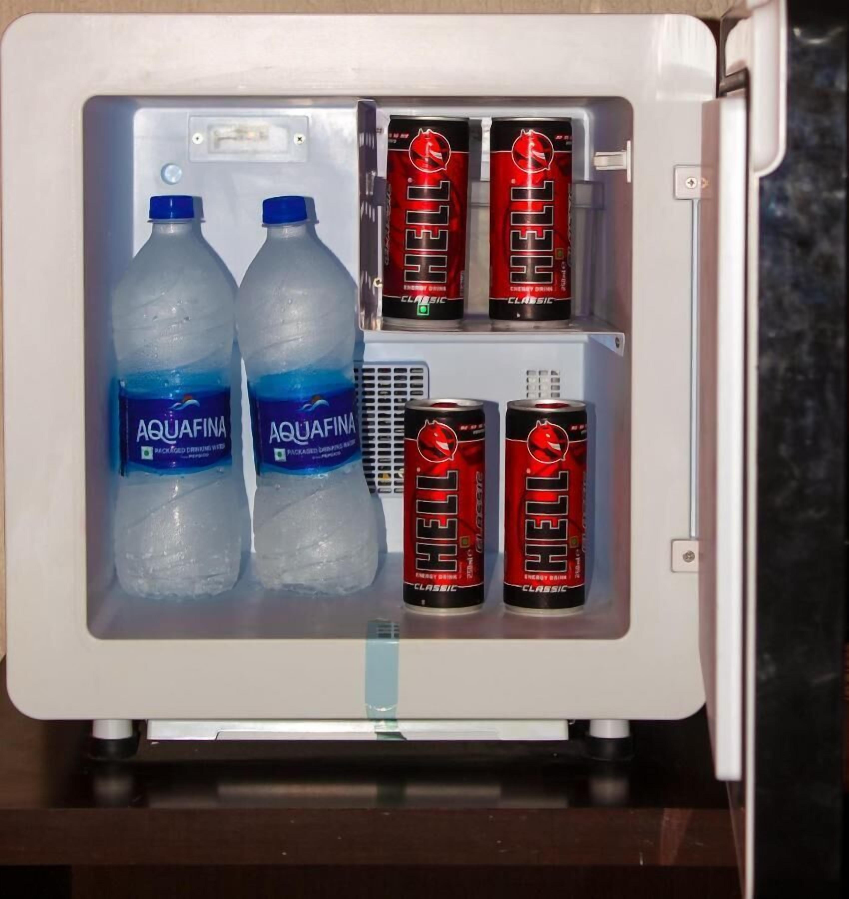 A mini-fridge containing two Aquafina water bottles and four cans of Red Bull Classic energy drink.