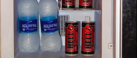 A mini-fridge containing two Aquafina water bottles and four cans of Red Bull Classic energy drink.