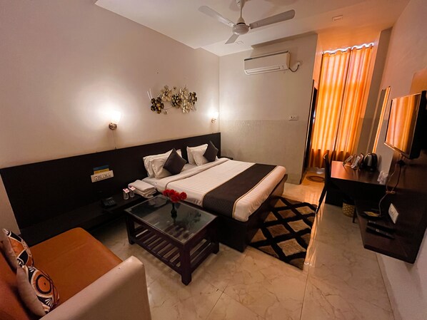 A hotel room with a bed, bedside table, chair, desk, and a ceiling fan.