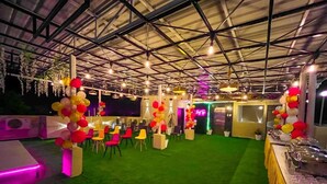 An indoor event space with a green carpet, chairs, and tables.