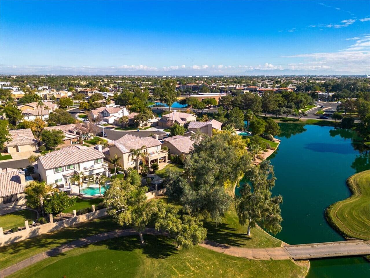 A residential area with houses, a swimming pool, and a body of water.