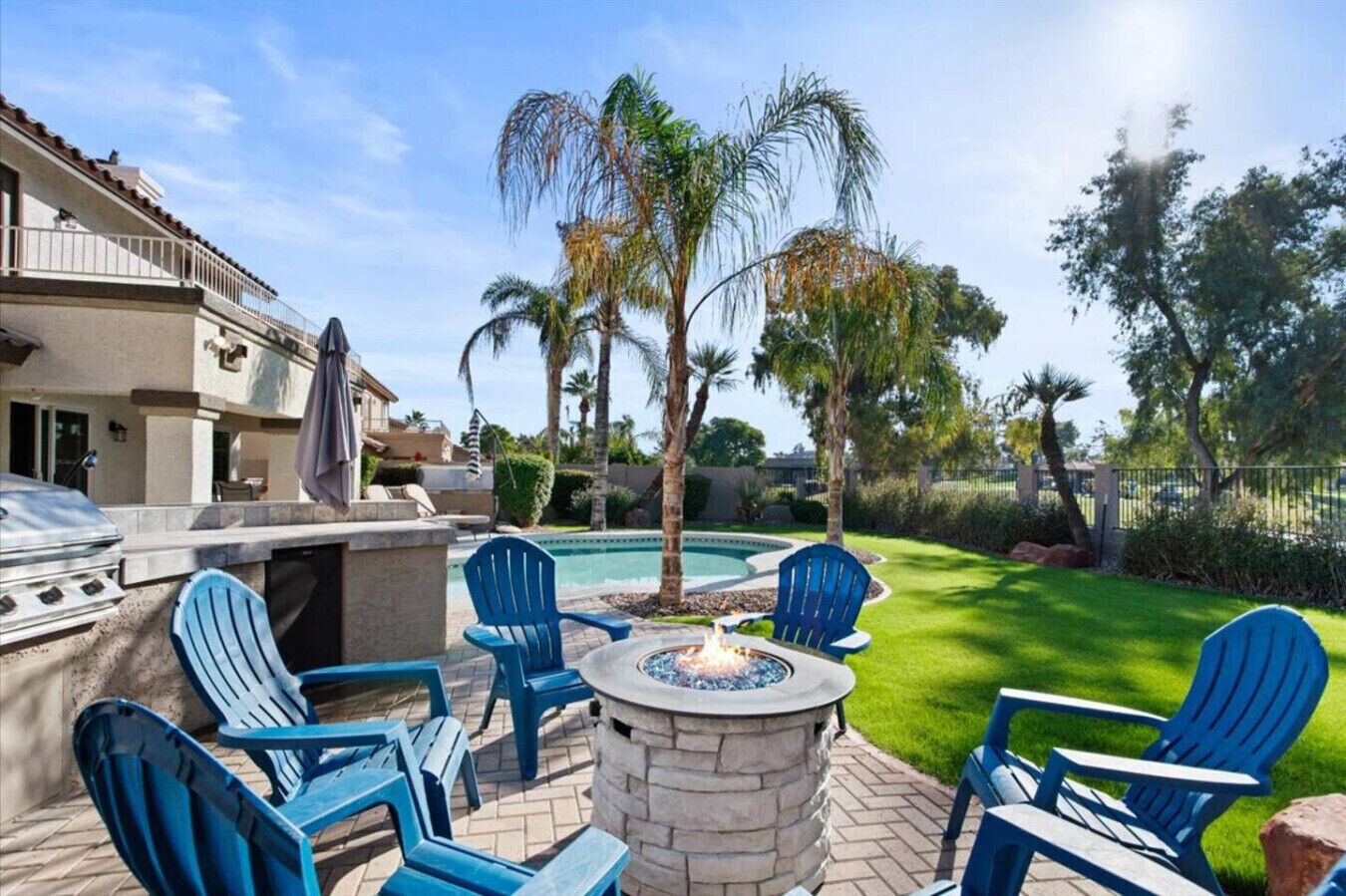 A patio with outdoor seating, a fire pit, and a swimming pool.