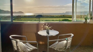 A balcony with a table and two chairs, overlooking a coastal landscape with a view of the sea and distant hills. - Waterfront fabulous view, spacious studio, heated pool & 10 mins walk into town. (Whitianga)
