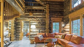 A log cabin interior with a curved leather sofa, a lamp, and a fireplace. - Menninkäisenkolo by Interhome (Äkäslompolo)