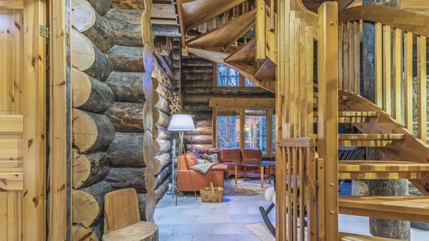 A log cabin interior with a staircase, wooden walls, a sofa, and a lamp. - Menninkäisenkolo by Interhome (Äkäslompolo)