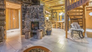 A log cabin interior with a stone fireplace, wooden furniture, and a staircase. - Menninkäisenkolo by Interhome (Äkäslompolo)