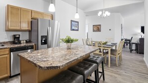 A modern kitchen with granite countertops, stainless steel appliances, wooden cabinets, and a central island with seating. - Brand New Duplex Close to Water Park, Downtown & Airport- Pet Friendly. (Montrose)