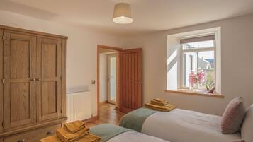 Une chambre avec deux lits, une armoire en bois, un radiateur et une fenêtre donnant sur un beau paysage.