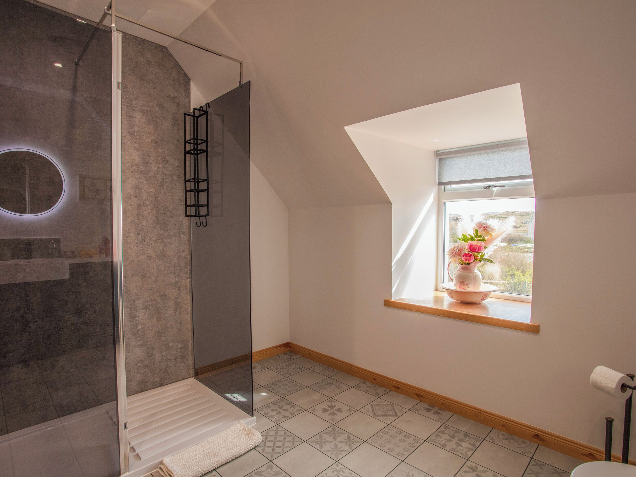Un baño moderno con cabina de ducha de vidrio, un tragaluz y vistas al exterior.